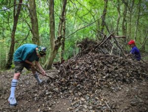 TRIBE Bushcraft child adventure day session children covering their mini shelter with leaves