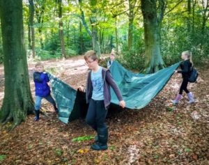 TRIBE Bushcraft child birthday party children carrying a tarp to an area between 2 trees