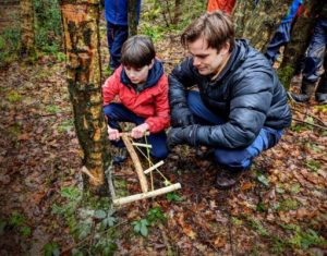 TRIBE Bushcraft home school education session child being shown by instructor how to fell a tree