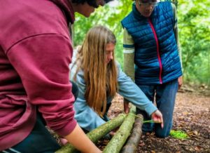 TRIBE Bushcraft home school education session children tying 3 poles together to make a tripod