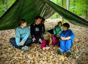 TRIBE Bushcraft school group booking children under completed tarp shelter