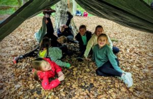 TRIBE Bushcraft school group booking children underneath a tarp shelter