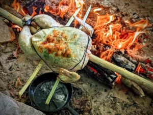 TRIBE Bushcraft session cooking a chicken on a spit