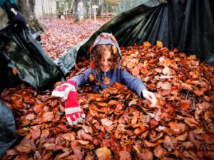 TRIBE Bushcraft session social saturdays family bushcraft child in leaves being gathered