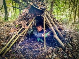 TRIBE Bushcraft session social saturdays family bushcraft child inside a mini shelter