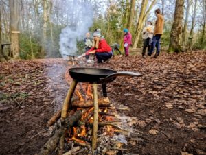 TRIBE Bushcraft session social saturdays family bushcraft pancackes being made over a small fire and 3 green sticks 3