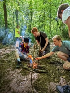 TRIBE Bushcraft youth group making a fire to burn the string on the fire ladder challenge