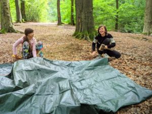 TRIBE Bushcraft child discovery day children putting tent pegs on a tarp shelter