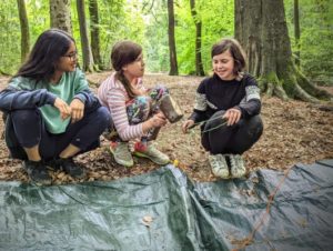 TRIBE Bushcraft child discovery day children putting tent pegs on a tarp shelter