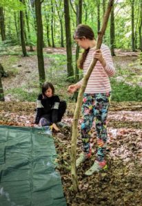 TRIBE Bushcraft child discovery day children putting tent pegs on a tarp shelter