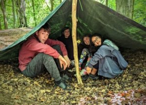 TRIBE Bushcraft child discovery day children sat in a tarp shelter they created