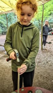 TRIBE Bushcraft session social saturdays family child putting a nail into a whimmy diddle toy